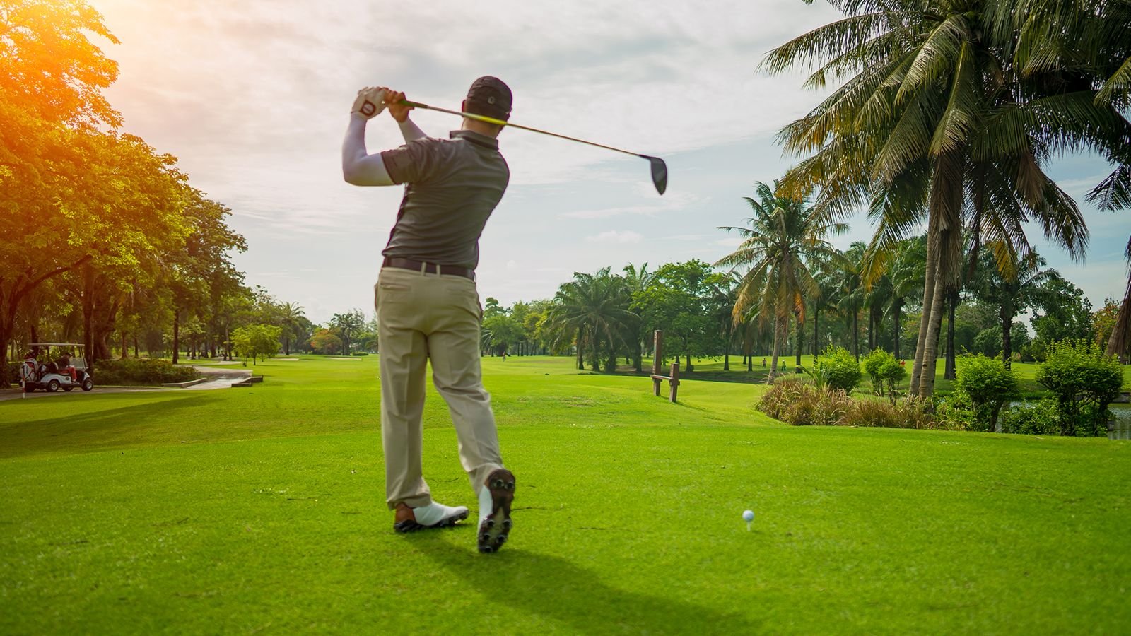Golfer completing a swing on a sunlit golf course